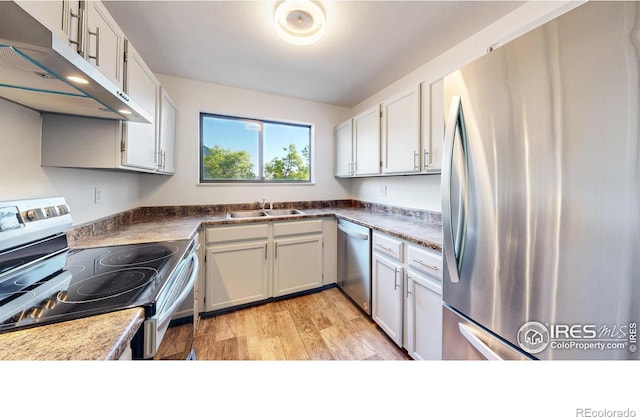 3526 S Depew St Unit 102, Lakewood, CO 80235 - kitchen featuring stainless steel appliances, under cabinet range hood, a sink, white cabinets, and light wood-type flooring
