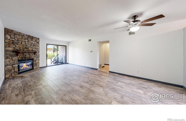 3526 S Depew St Unit 102, Lakewood, CO 80235 - unfurnished living room featuring wood finished floors, ceiling fan, a stone fireplace, and baseboards