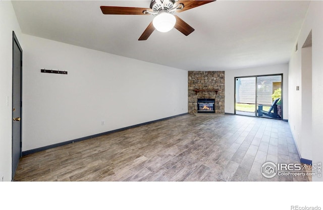 3526 S Depew St Unit 102, Lakewood, CO 80235 - unfurnished living room with wood finished floors, ceiling fan, a stone fireplace, and baseboards