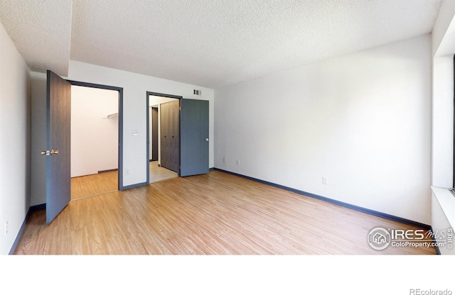 3526 S Depew St Unit 102, Lakewood, CO 80235 - unfurnished bedroom featuring light wood-type flooring, a textured ceiling, and baseboards