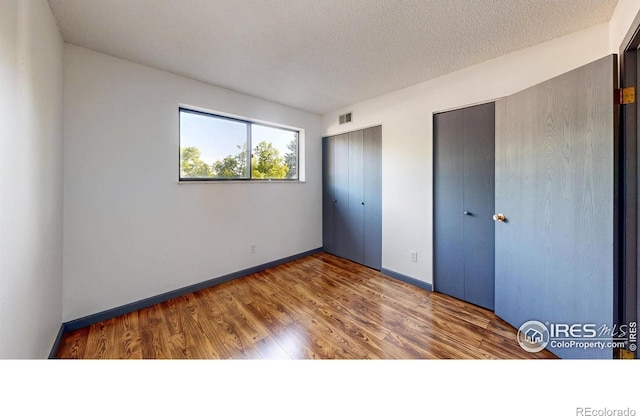 3526 S Depew St Unit 102, Lakewood, CO 80235 - unfurnished bedroom with two closets, baseboards, wood finished floors, and a textured ceiling