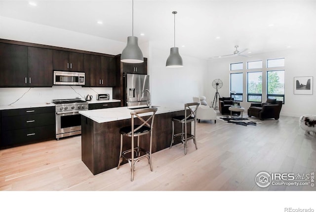 1769 Beachside Dr, Windsor, CO 80550 - kitchen with stainless steel appliances, a kitchen breakfast bar, light wood-type flooring, recessed lighting, and a kitchen island with sink