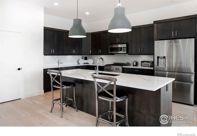 1769 Beachside Dr, Windsor, CO 80550 - kitchen with stainless steel appliances, a sink, a breakfast bar, light wood-style flooring, and hanging light fixtures