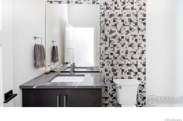 1769 Beachside Dr, Windsor, CO 80550 - half bathroom featuring toilet, vanity, and tile walls
