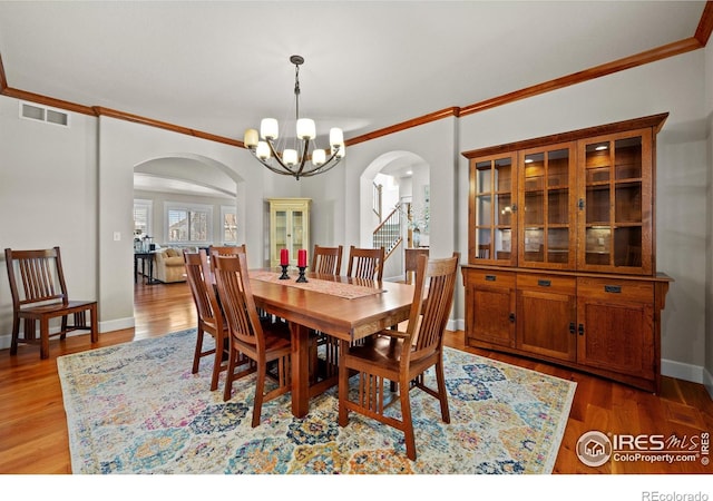 2005 Calico Ct, Longmont, CO 80503 - dining space with arched walkways, a chandelier, ornamental molding, wood finished floors, and baseboards
