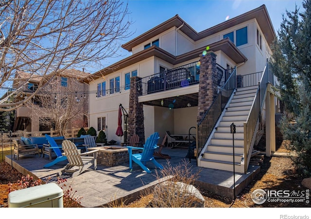 2005 Calico Ct, Longmont, CO 80503 - back of property with stucco siding, a patio area, an outdoor fire pit, and stairway