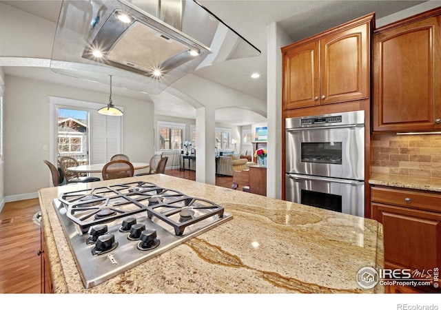 2005 Calico Ct, Longmont, CO 80503 - kitchen with stainless steel appliances, light wood-style floors, arched walkways, backsplash, and light stone countertops