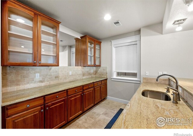 2005 Calico Ct, Longmont, CO 80503 - kitchen featuring a sink, glass insert cabinets, light stone countertops, baseboards, and tasteful backsplash