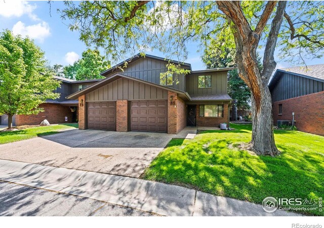 2840 W 21st St Unit 14, Greeley, CO 80634 - view of front facade with a garage, brick siding, a front lawn, concrete driveway, and cooling unit