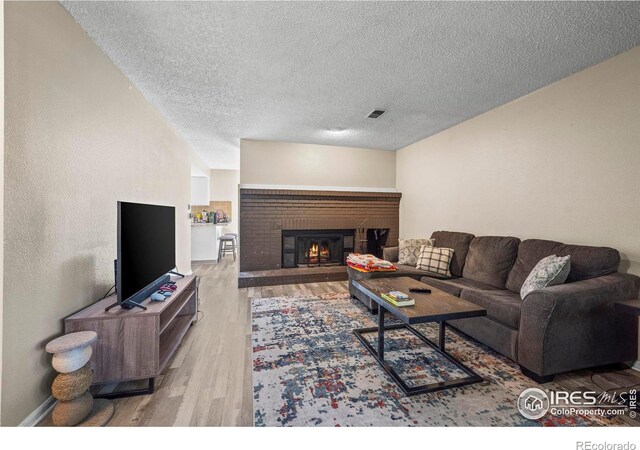2840 W 21st St Unit 14, Greeley, CO 80634 - living area featuring wood finished floors, a fireplace, a textured ceiling, and baseboards