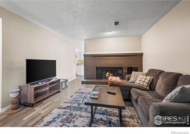 2840 W 21st St Unit 14, Greeley, CO 80634 - living room with wood finished floors, baseboards, a fireplace, and a textured ceiling