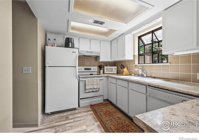 2840 W 21st St Unit 14, Greeley, CO 80634 - kitchen featuring white appliances, light wood-style floors, under cabinet range hood, a sink, and tasteful backsplash