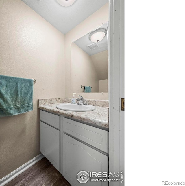 2840 W 21st St Unit 14, Greeley, CO 80634 - bathroom featuring vanity, baseboards, and wood finished floors