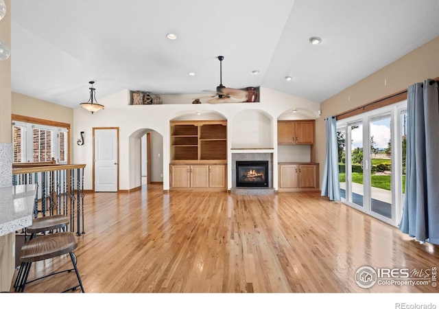 29 Pioneer Pl, Eaton, CO 80615 - unfurnished living room featuring vaulted ceiling, light wood-style floors, a glass covered fireplace, ceiling fan, and arched walkways