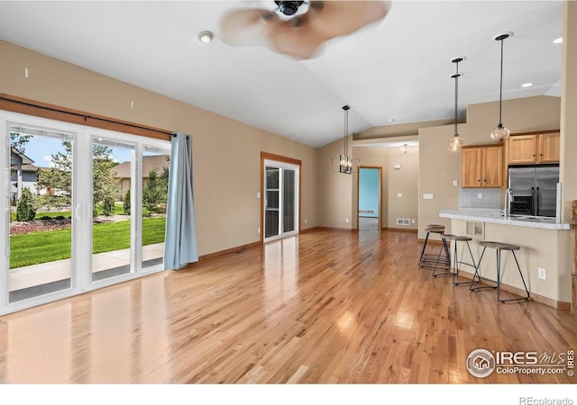 29 Pioneer Pl, Eaton, CO 80615 - kitchen featuring stainless steel refrigerator with ice dispenser, ceiling fan, light wood finished floors, decorative backsplash, and lofted ceiling