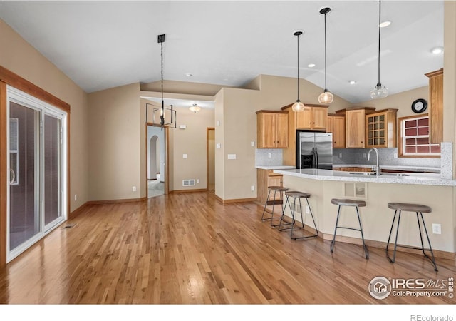 29 Pioneer Pl, Eaton, CO 80615 - kitchen featuring stainless steel refrigerator with ice dispenser, vaulted ceiling, a sink, a breakfast bar area, and light wood finished floors