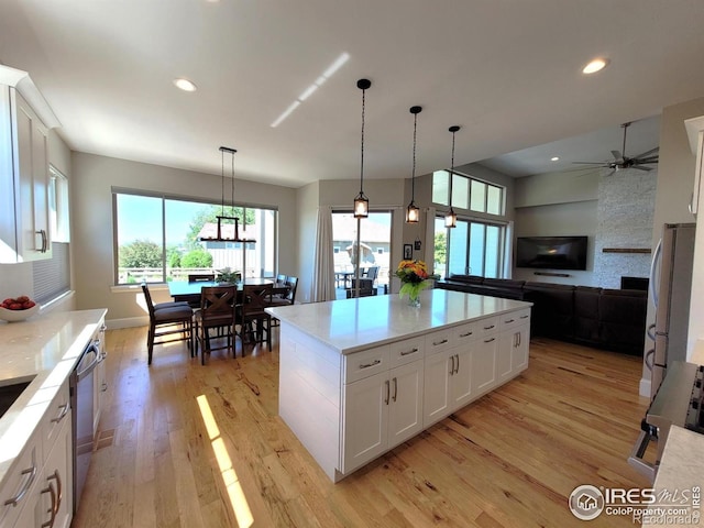 4236 Carroway Seed Ct, Johnstown, CO 80534 - kitchen with stainless steel dishwasher, light wood-style flooring, ceiling fan, a center island, and light countertops