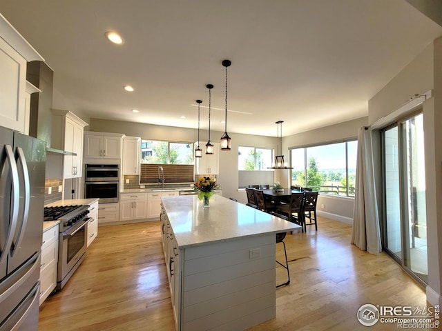 4236 Carroway Seed Ct, Johnstown, CO 80534 - kitchen featuring appliances with stainless steel finishes, recessed lighting, a center island, white cabinets, and light wood-style flooring