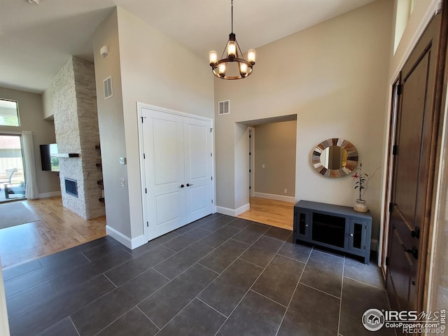 4236 Carroway Seed Ct, Johnstown, CO 80534 - foyer with a high ceiling, a chandelier, baseboards, dark tile patterned flooring, and a fireplace
