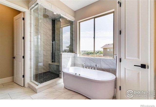 4236 Carroway Seed Ct, Johnstown, CO 80534 - bathroom featuring a shower stall, a soaking tub, marble look tile flooring, and baseboards