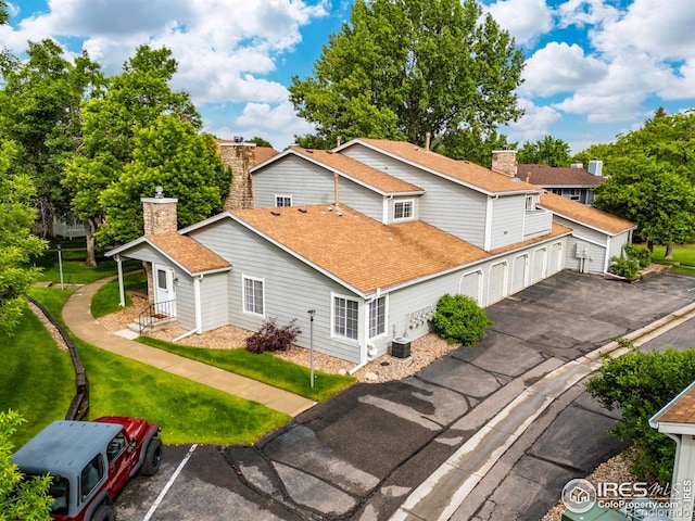 8423 Everett Way Unit A, Arvada, CO 80005 - view of property exterior with a chimney, a shingled roof, a garage, a lawn, and central AC unit