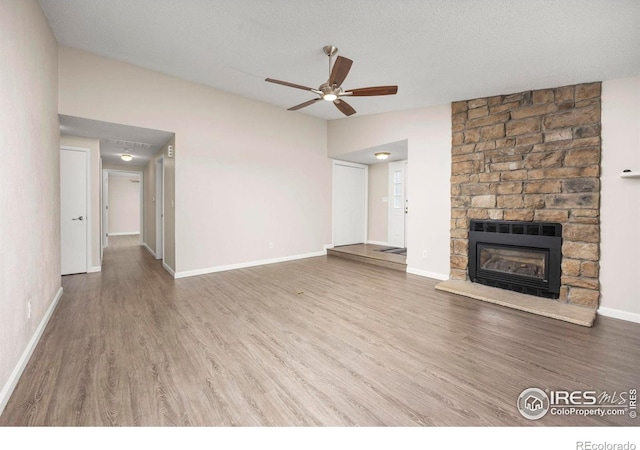 8423 Everett Way Unit A, Arvada, CO 80005 - unfurnished living room with wood finished floors, a ceiling fan, a stone fireplace, and baseboards
