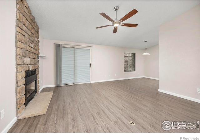 8423 Everett Way Unit A, Arvada, CO 80005 - unfurnished living room with a ceiling fan, wood finished floors, a fireplace, baseboards, and lofted ceiling