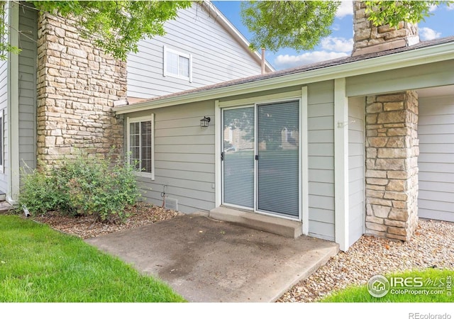 8423 Everett Way Unit A, Arvada, CO 80005 - doorway to property with stone siding, a chimney, and a patio area