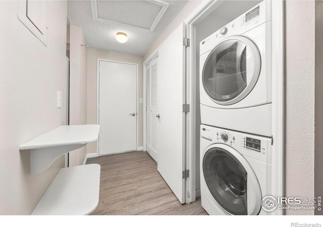 8423 Everett Way Unit A, Arvada, CO 80005 - laundry room featuring stacked washer and clothes dryer, light wood-style floors, and a textured ceiling