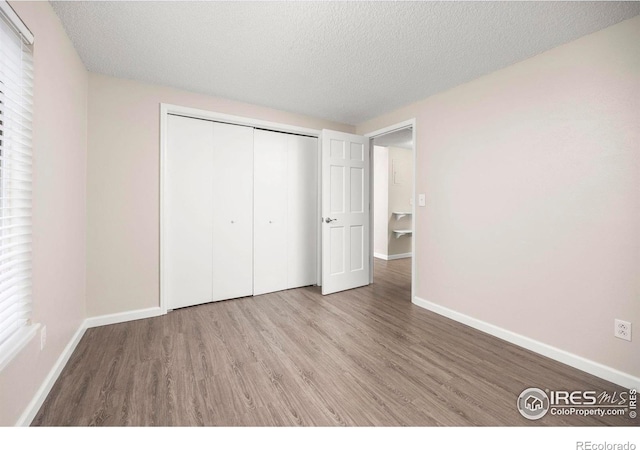 8423 Everett Way Unit A, Arvada, CO 80005 - unfurnished bedroom featuring wood finished floors, baseboards, a closet, and a textured ceiling