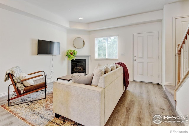 1240 Wren Ct Unit D, Longmont, CO 80501 - living room featuring light wood-style flooring, a glass covered fireplace, recessed lighting, baseboards, and stairway