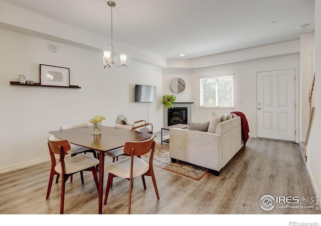 1240 Wren Ct Unit D, Longmont, CO 80501 - dining space featuring light wood-style flooring, a glass covered fireplace, a chandelier, and baseboards