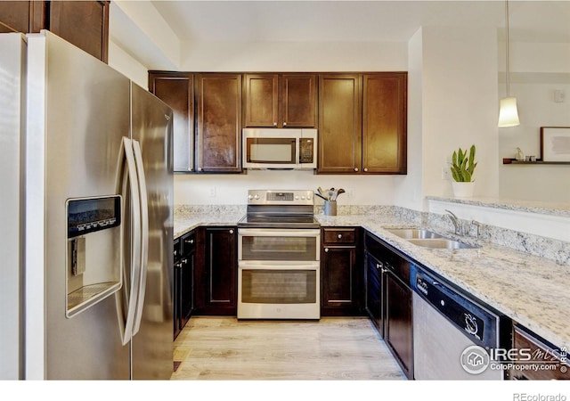 1240 Wren Ct Unit D, Longmont, CO 80501 - kitchen featuring appliances with stainless steel finishes, a sink, light wood-style floors, light stone counters, and pendant lighting