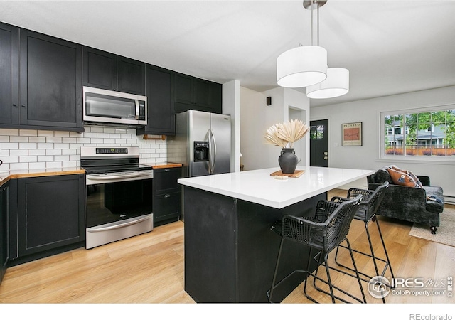 4329 Main St, Timnath, CO 80547 - kitchen featuring stainless steel appliances, dark cabinets, light wood-style flooring, and a kitchen bar