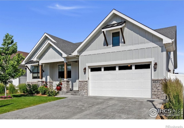 4521 Devereux Dr, Windsor, CO 80550 - view of front of house with stone siding, board and batten siding, driveway, a garage, and roof with shingles