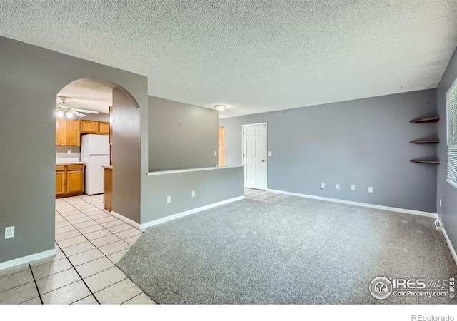 701 Elm St, Windsor, CO 80550 - spare room with a ceiling fan, baseboards, light tile patterned floors, arched walkways, and a textured ceiling