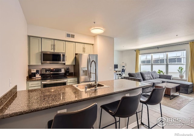 1623 Saint Paul St Unit 310, Denver, CO 80206 - kitchen featuring stainless steel appliances, a breakfast bar, open floor plan, a sink, and light wood-style floors