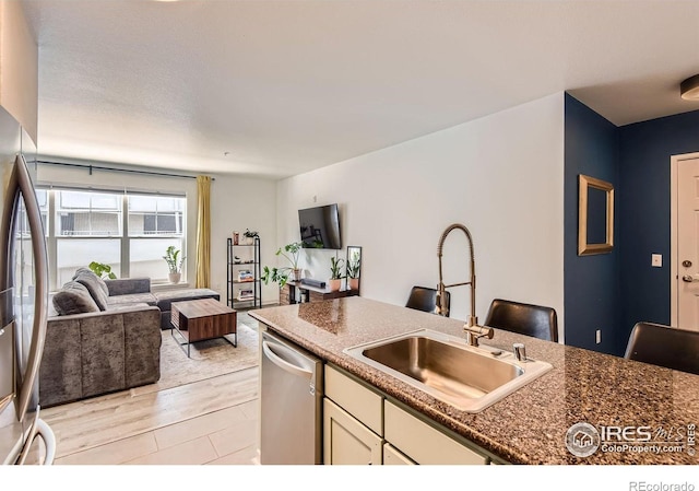 1623 Saint Paul St Unit 310, Denver, CO 80206 - kitchen with a sink, stainless steel appliances, open floor plan, white cabinets, and light wood-type flooring