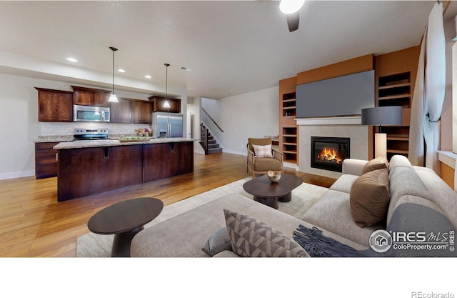 2107 Blackbird Dr, Fort Collins, CO 80525 - living area featuring stairway, light wood-type flooring, recessed lighting, a tiled fireplace, and ceiling fan