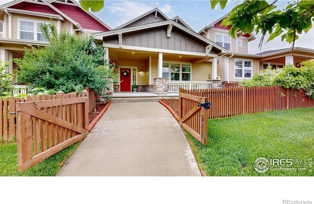 2107 Blackbird Dr, Fort Collins, CO 80525 - craftsman-style house with covered porch, a gate, a fenced front yard, board and batten siding, and stone siding