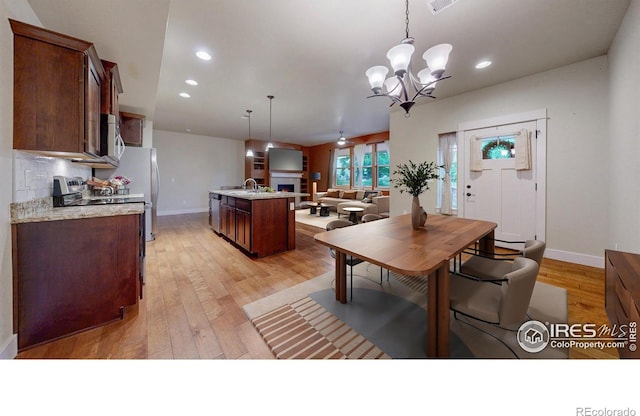 2107 Blackbird Dr, Fort Collins, CO 80525 - dining space with light wood-style flooring, a chandelier, a warm lit fireplace, and recessed lighting