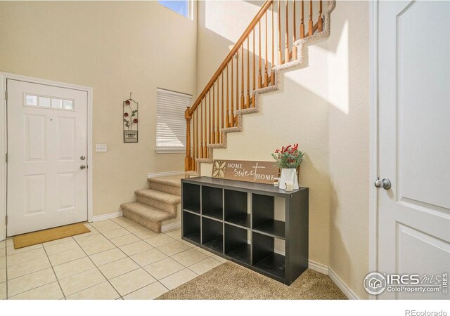 5551 29th St, Greeley, CO 80634 - foyer entrance featuring stairs, a towering ceiling, baseboards, light tile patterned flooring, and healthy amount of natural light