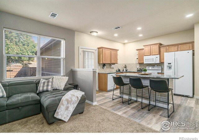5551 29th St, Greeley, CO 80634 - kitchen with white appliances, a center island, a kitchen bar, backsplash, and open floor plan