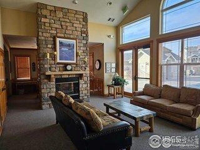 5551 29th St, Greeley, CO 80634 - carpeted living room with healthy amount of natural light, a stone fireplace, and high vaulted ceiling