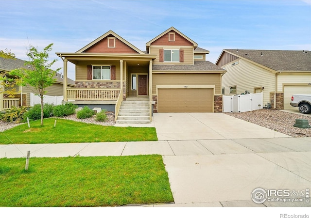 1711 101st Avenue Ct, Greeley, CO 80634 - view of front facade featuring stone siding, a porch, a garage, concrete driveway, and a gate