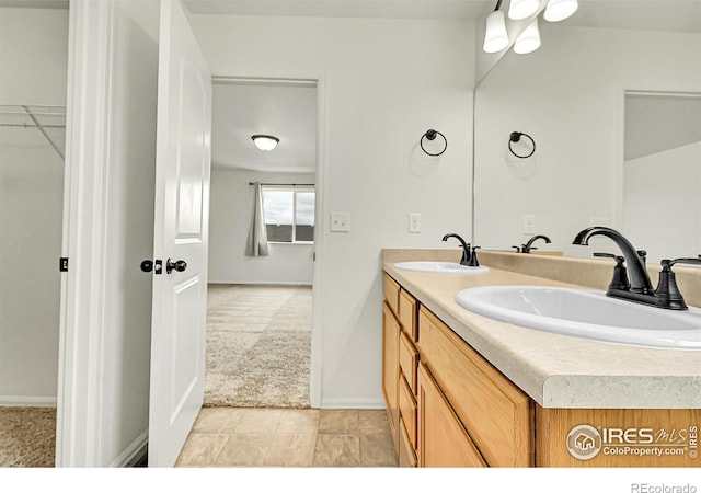 1711 101st Avenue Ct, Greeley, CO 80634 - bathroom featuring double vanity, a spacious closet, and baseboards