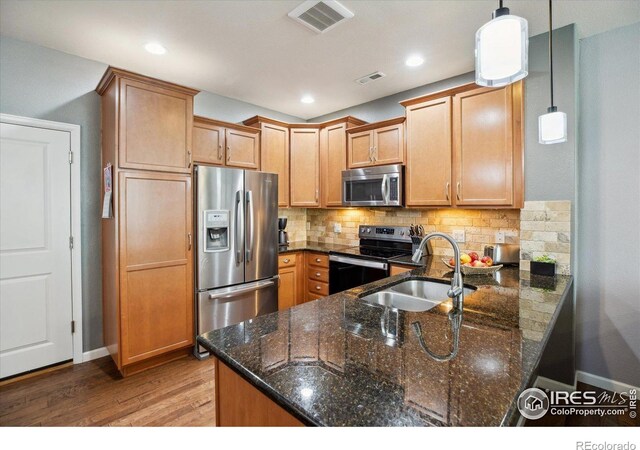 16031 W 63rd Ln W Unit D, Arvada, CO 80403 - kitchen with appliances with stainless steel finishes, a sink, wood finished floors, a peninsula, and decorative backsplash