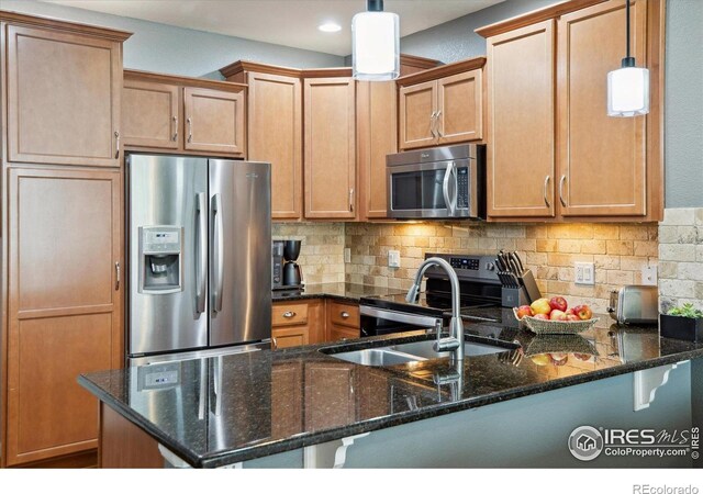 16031 W 63rd Ln W Unit D, Arvada, CO 80403 - kitchen with appliances with stainless steel finishes, backsplash, a peninsula, dark stone counters, and decorative light fixtures
