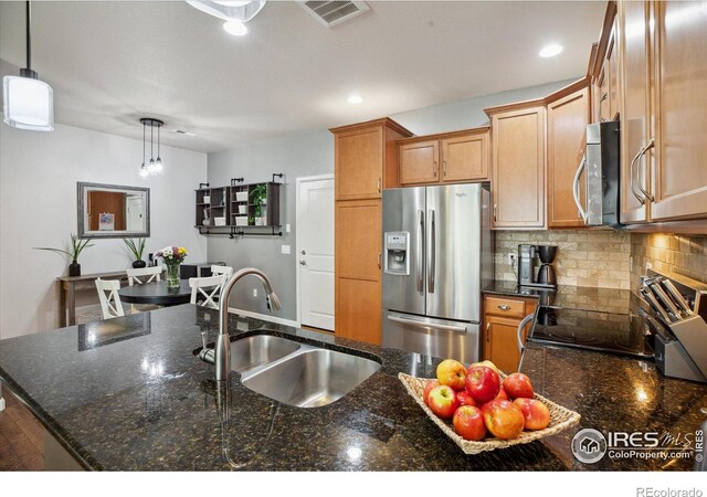 16031 W 63rd Ln W Unit D, Arvada, CO 80403 - kitchen with appliances with stainless steel finishes, a sink, decorative backsplash, pendant lighting, and brown cabinetry