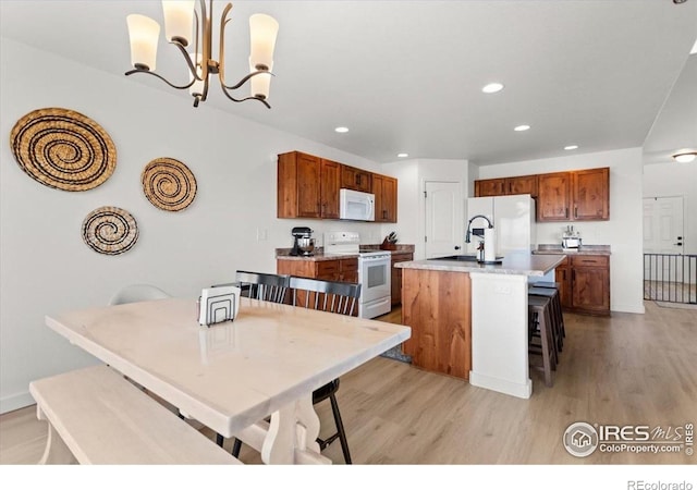1718 101st Avenue Ct, Greeley, CO 80634 - kitchen featuring white appliances, a sink, light wood-style floors, a kitchen island with sink, and recessed lighting